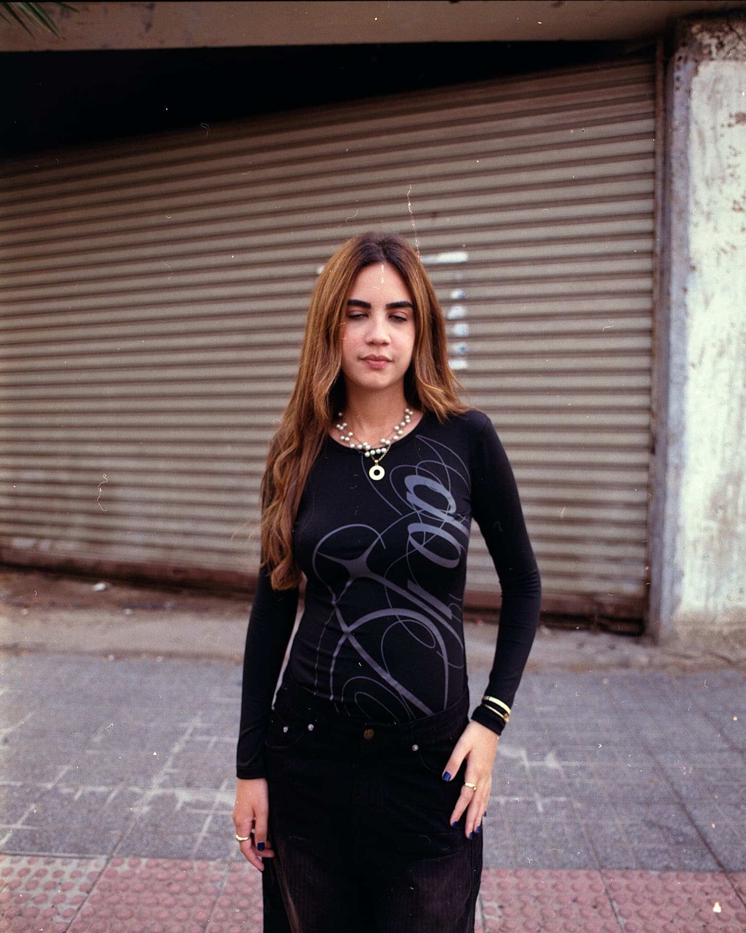 Portrait of a model in front of a metal shutter wearing a DROP script long sleeve