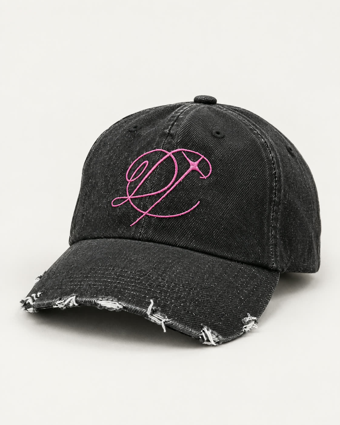 Scarred Denim Hat in washed black, three-quarter front view with pink DROP script embroidery and distressed brim