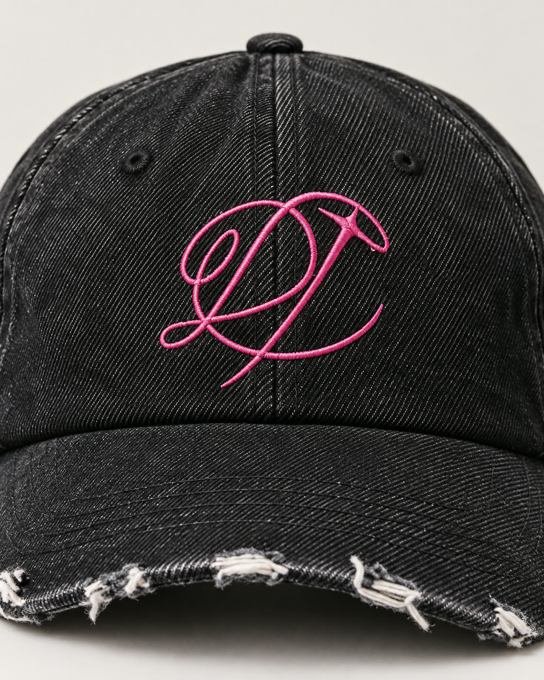 Close-up of the pink embroidered DROP graphic on the front of the black denim hat