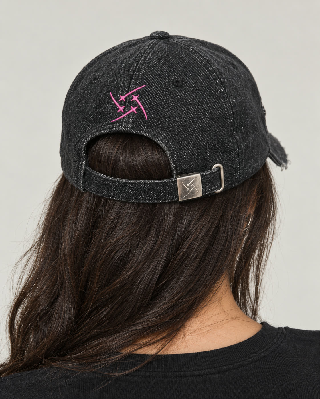 Back view of the Scarred Denim Hat worn by a model, showing the pink star embroidery and metal-adjustable strap