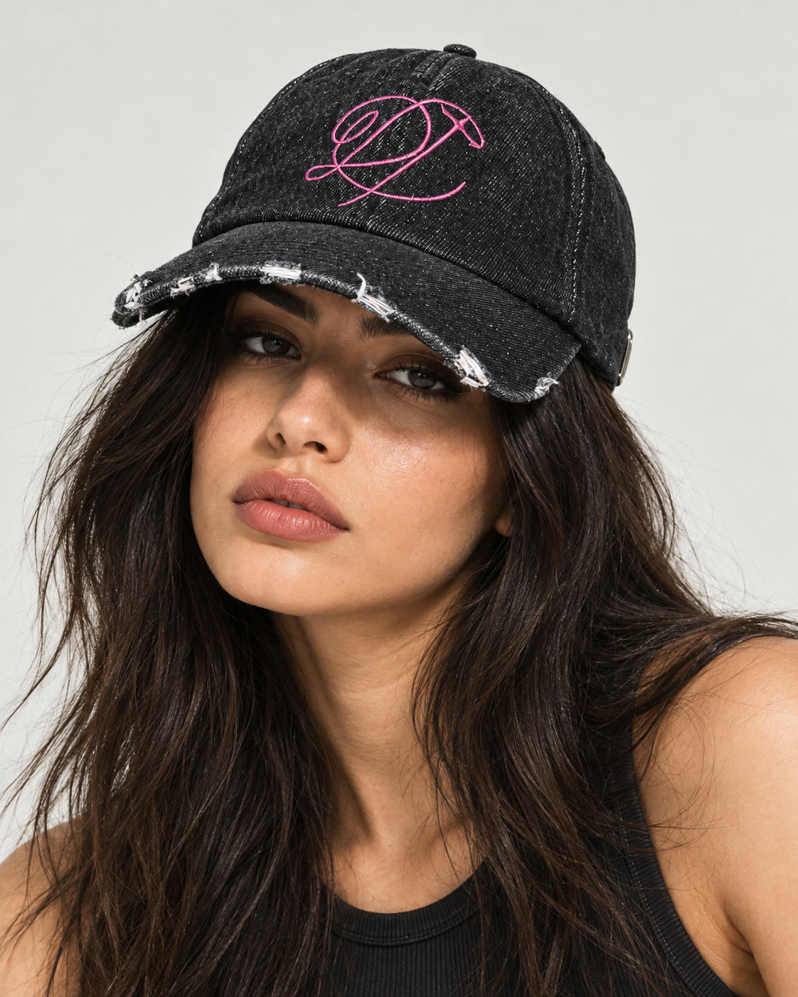 Model wearing the black distressed denim DROP cap with pink embroidery