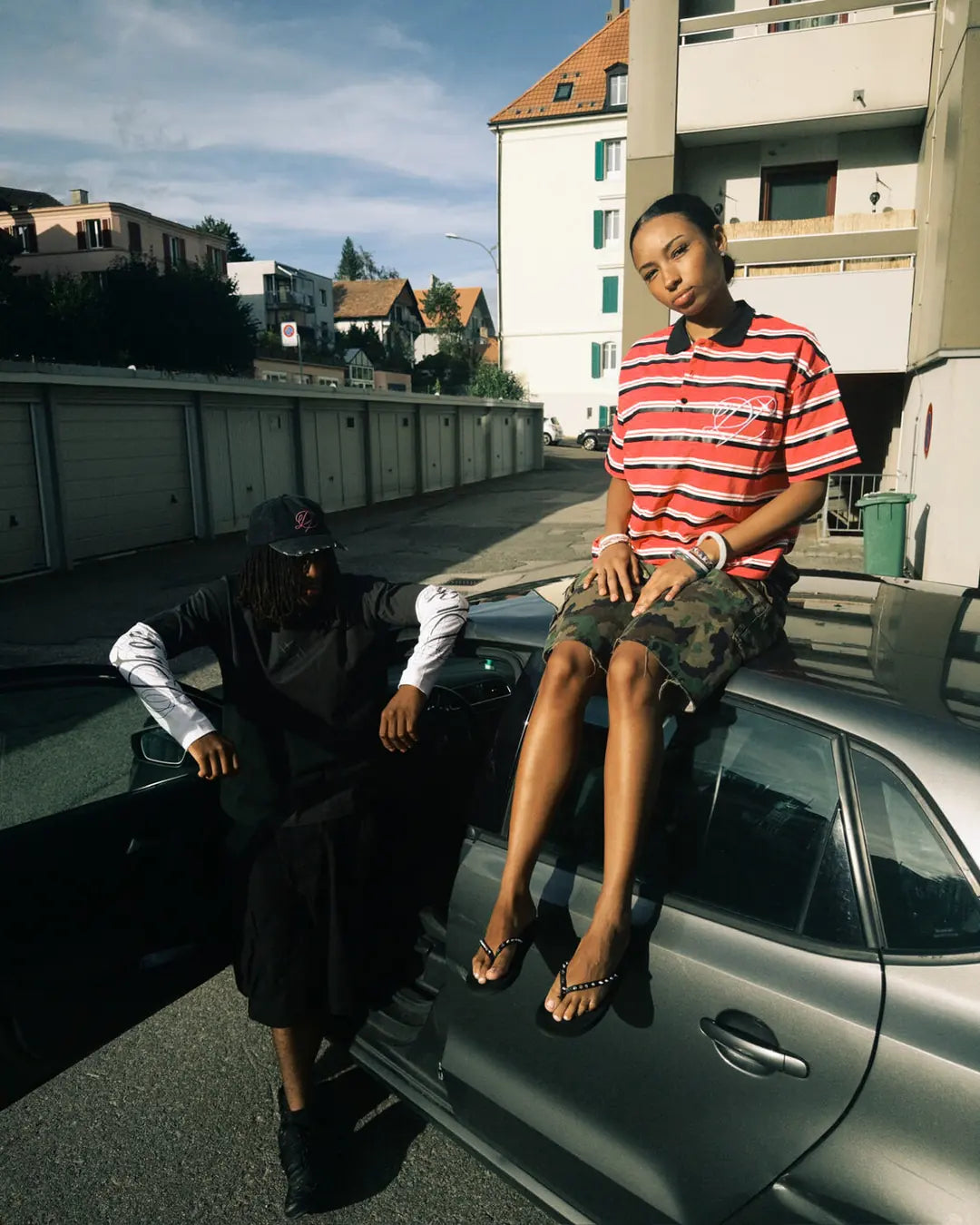 Two models in Heritage pieces beside a car on a residential street