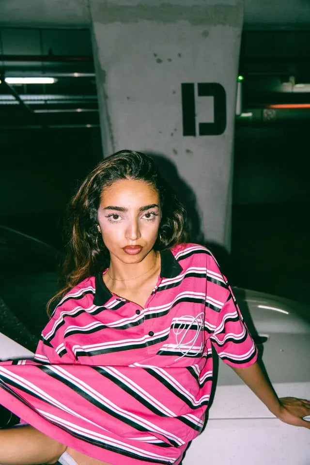Model in the striped Heritage polo leaning against a car in a parking garage