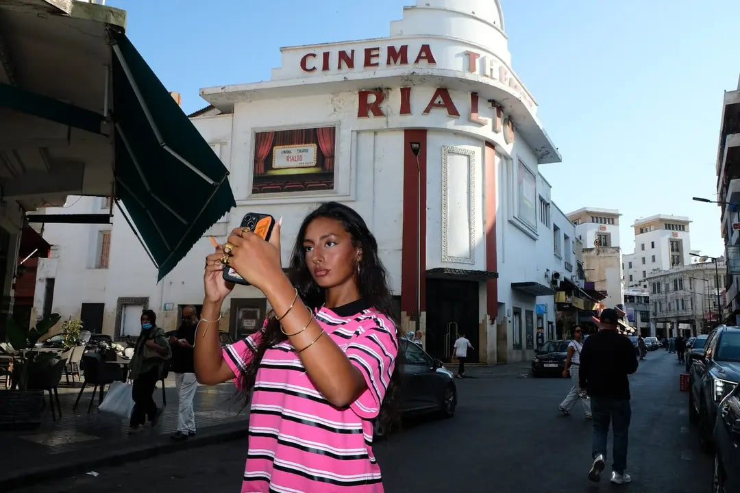 Model in the striped Heritage polo on a street in front of the Cinéma Rialto