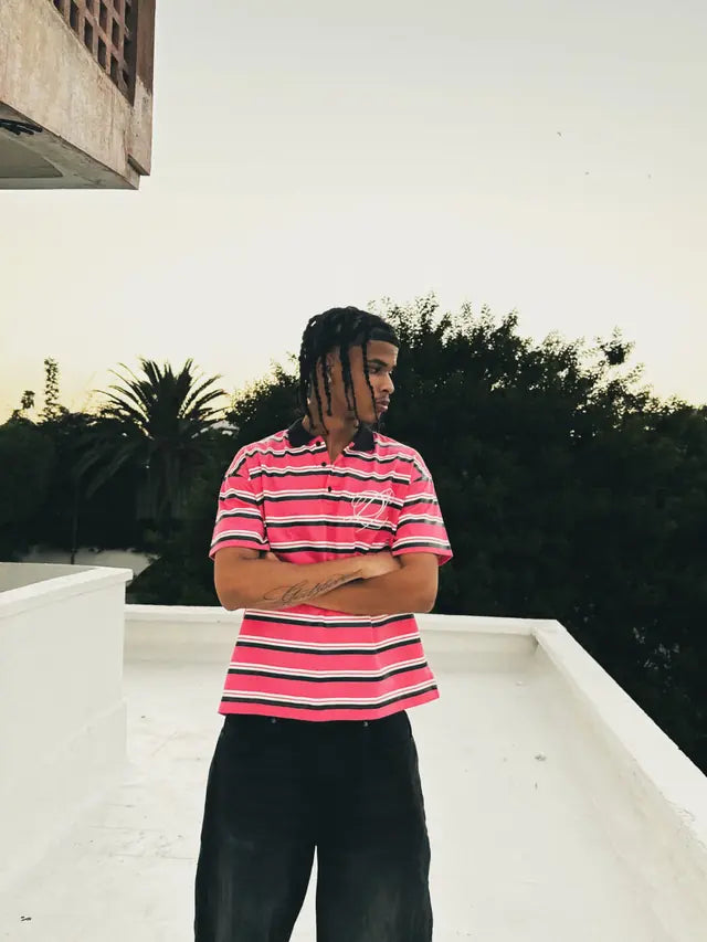 Model in the striped Heritage polo on a rooftop at dusk