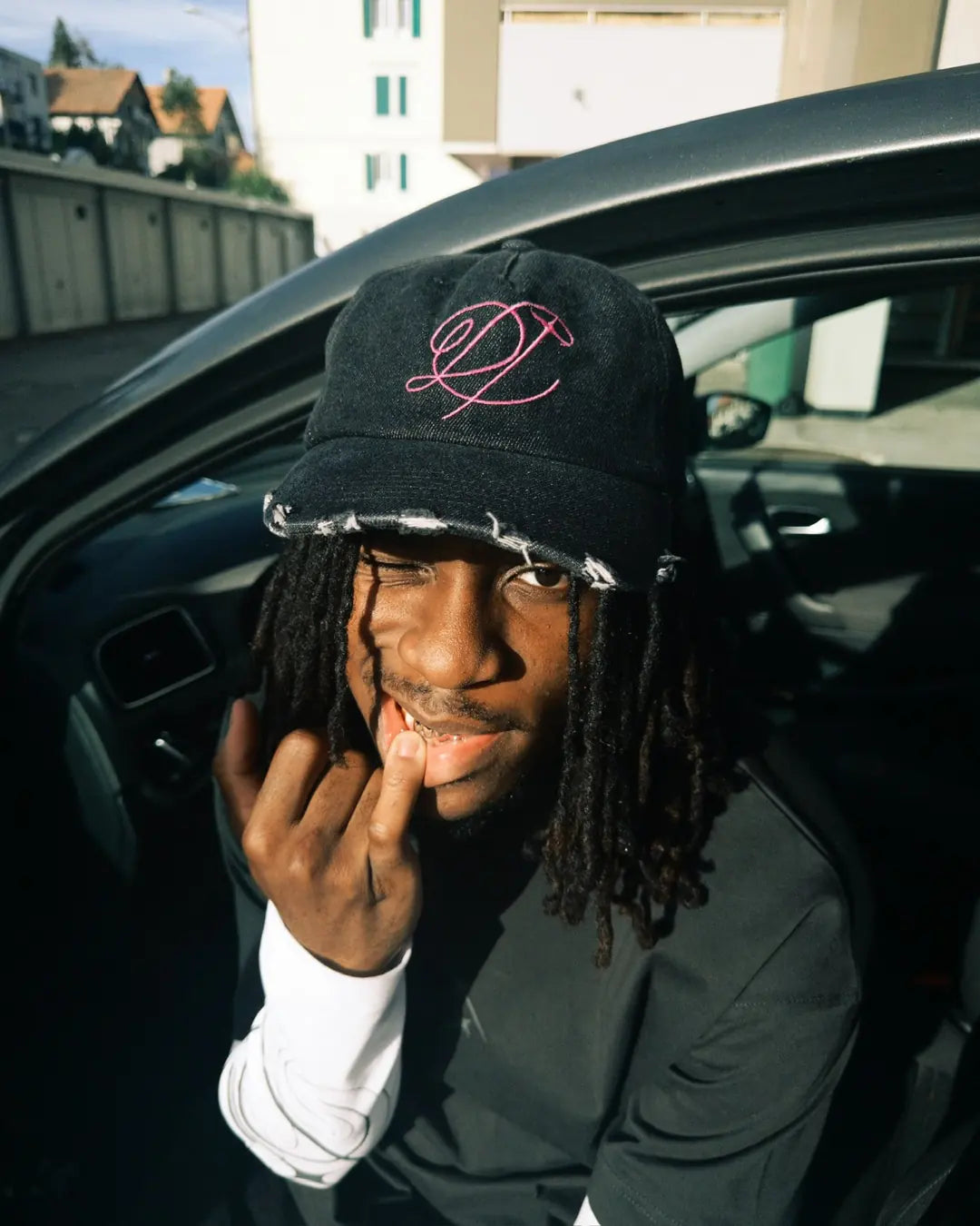 Model wearing the black DROP cap by a car